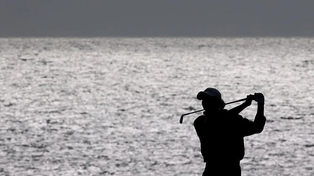 A silhouette image of Charley Hull as she plays a shot on 18 at Royal Porthcawl