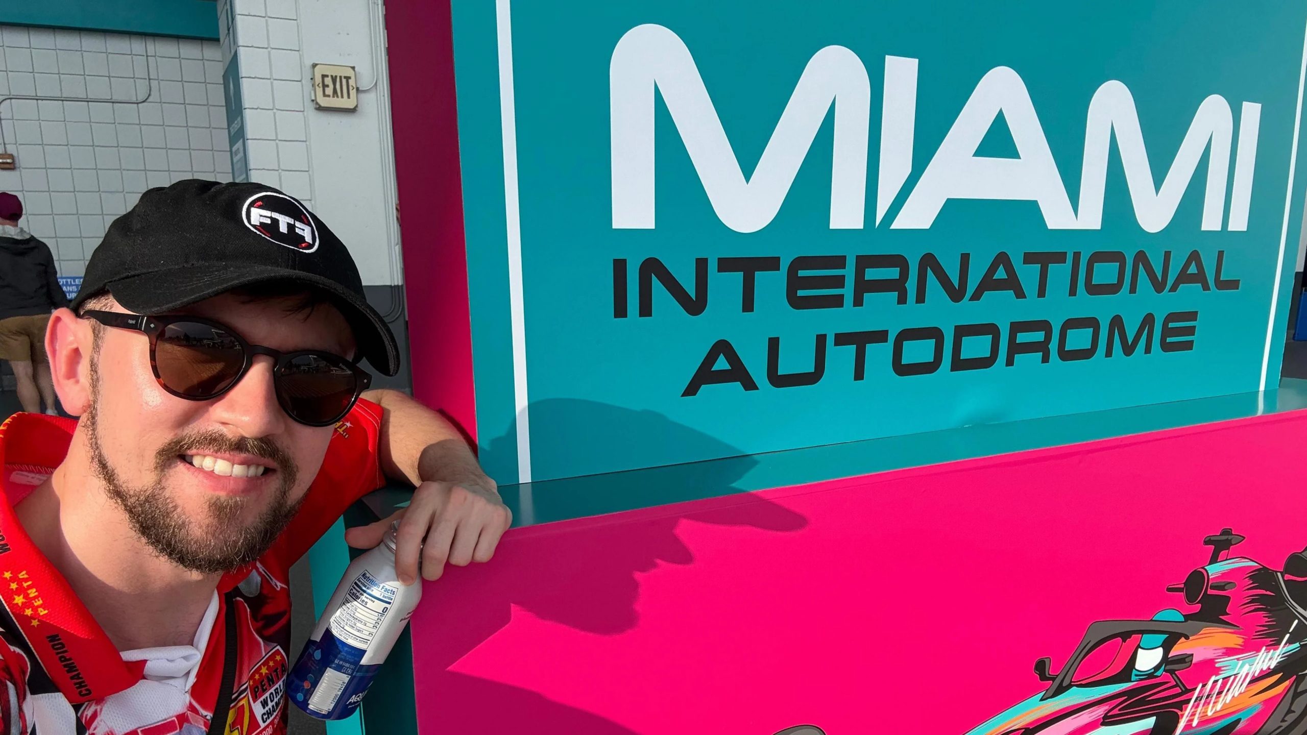 Brandon Burgess poses for a selfie alongside a 'Miami International Autodrome' sign