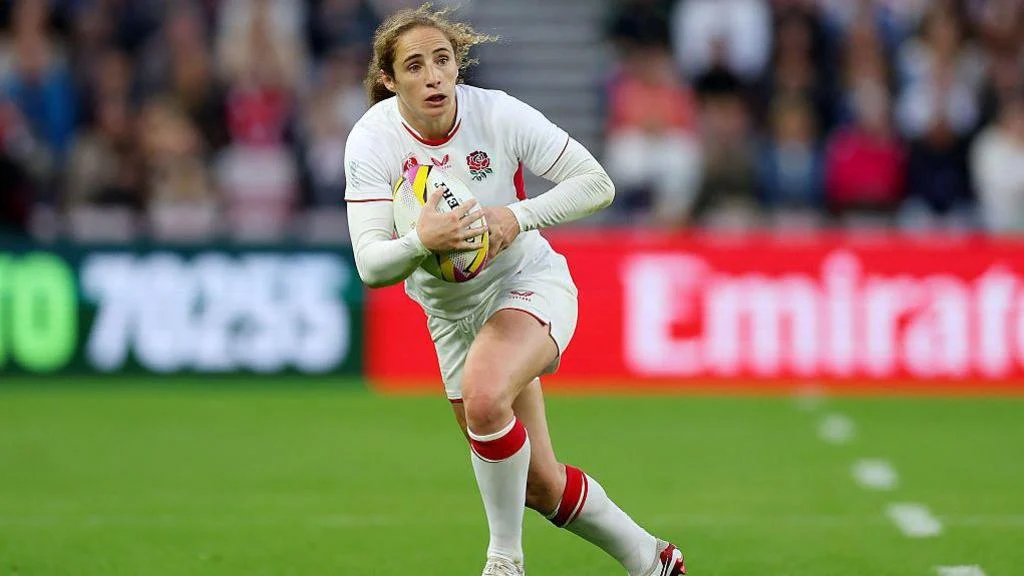 A picture of Red Rose Abby Dow running with the World Cup ball