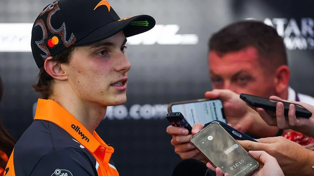 McLaren's Oscar Piastri speaking to journalists, many of whom are holding up phones to record the interview, following the United States Grand Prix