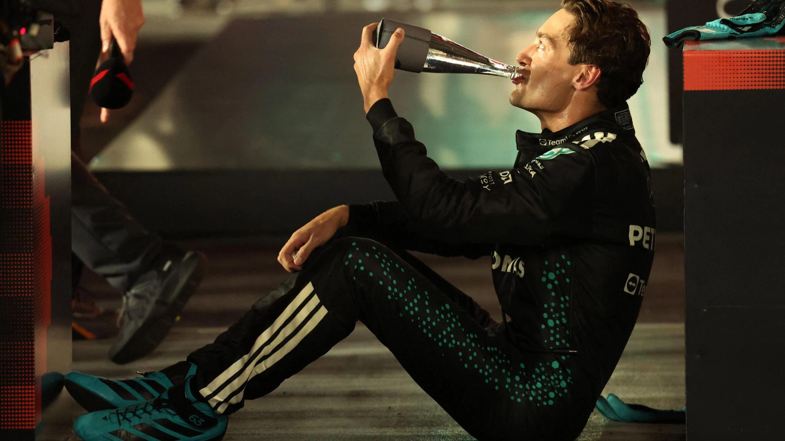 George Russell sits down, rests and and drinks from a water bottle after winning the Singapore Grand Prix