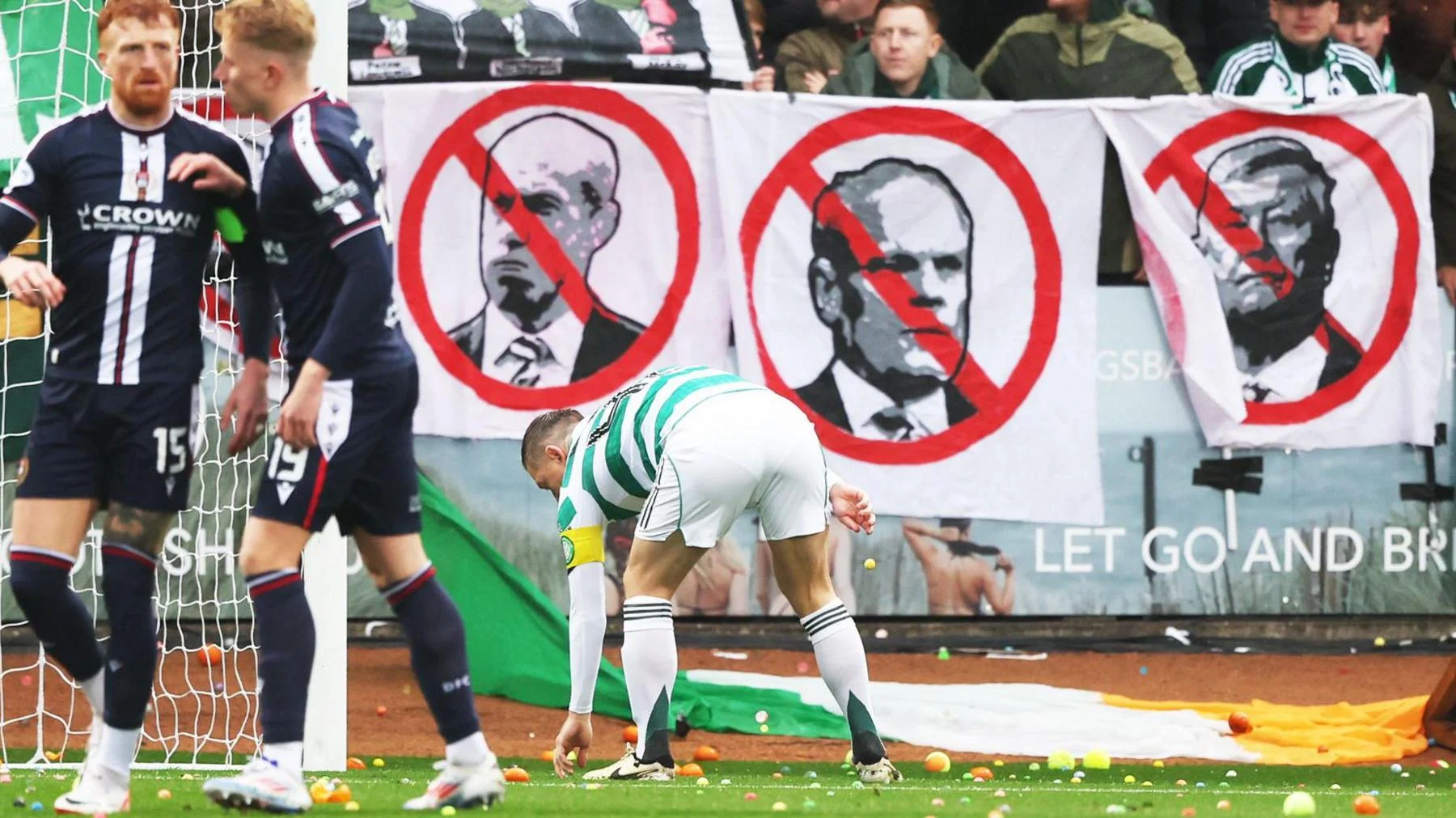 Celtic captain Callum McGregor picks up bouncy balls thrown onto the Dens Park pitch by Celtic supporters